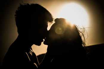 silhouettes of couple kissing against sunset